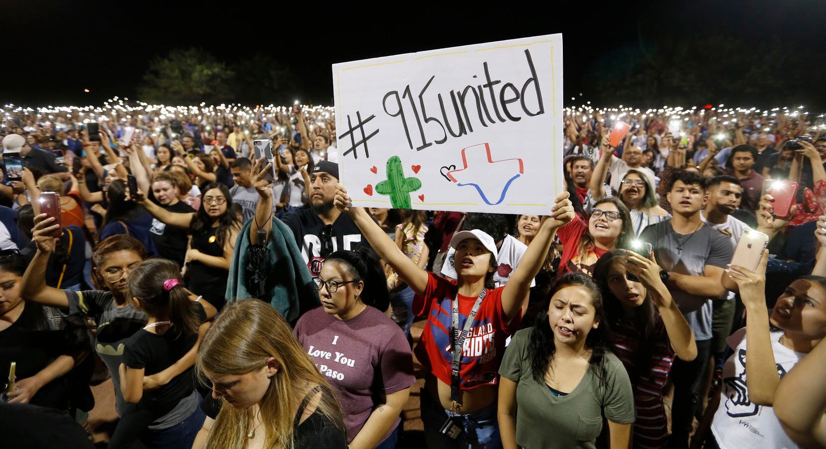 Iliani Ibarra of El Paso held up a sign as others held their phones during a vigil at Ponder...