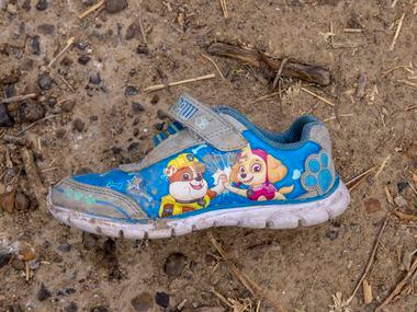 A single abandoned child’s shoe is among the belongings left behind by migrants in the rural...