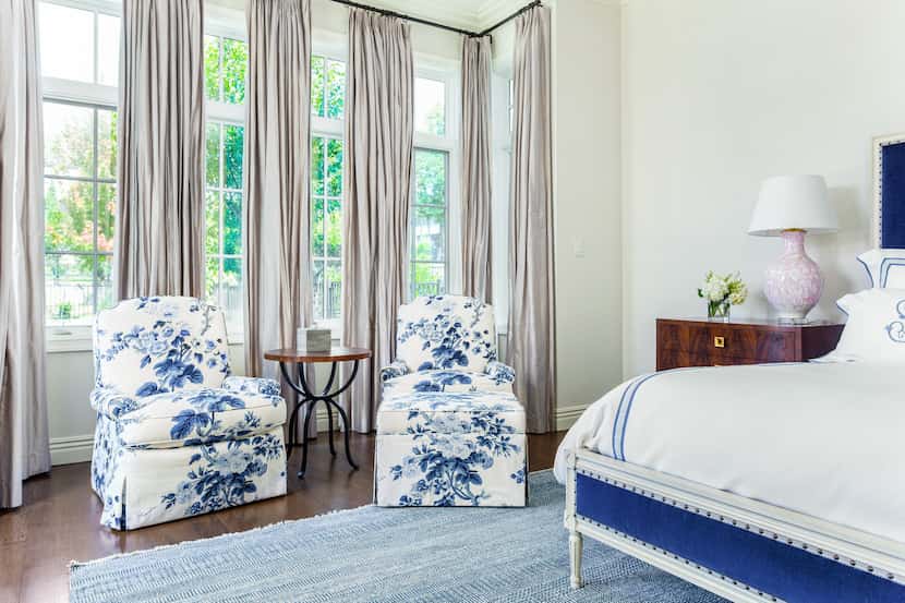 A bedroom has a seating area with two chairs with floral blue pattern