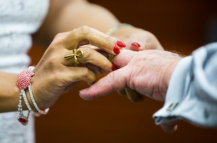 Zoriapeter Joseph slips a wedding ring on the finger of James Albert Schoen as they are...