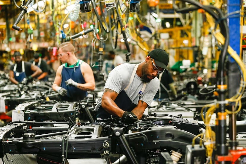 General Motors employees work on the assembly line at the company's Arlington assembly...
