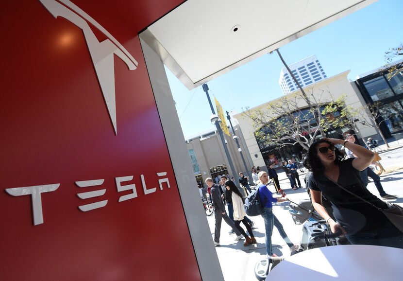 A woman looks into the Tesla store in Santa Monica, California, where customers are waiting...