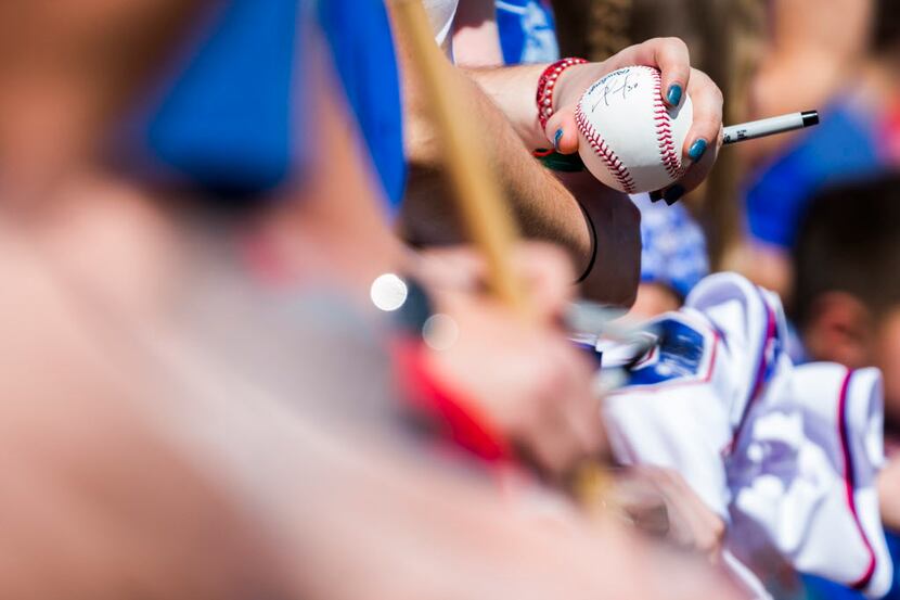 A Texas Rangers fan holds a signed baseball before a spring training baseball game against...
