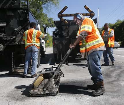 Dallas Street Services employee Ricky King (front) works with others to fix a pothole on...