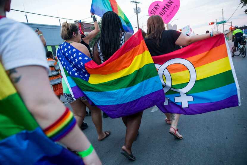 Attendees of a 2016 march walk though Deep Ellum carrying rainbow flags in this file photo....