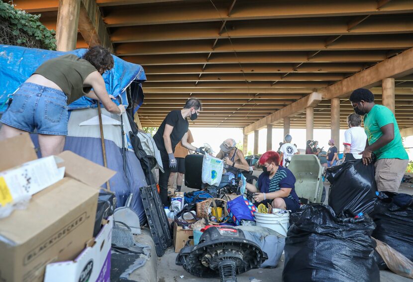 Volunteers help Randy "Cowboy" Briscoe (center) temporarily move his tent and personal...