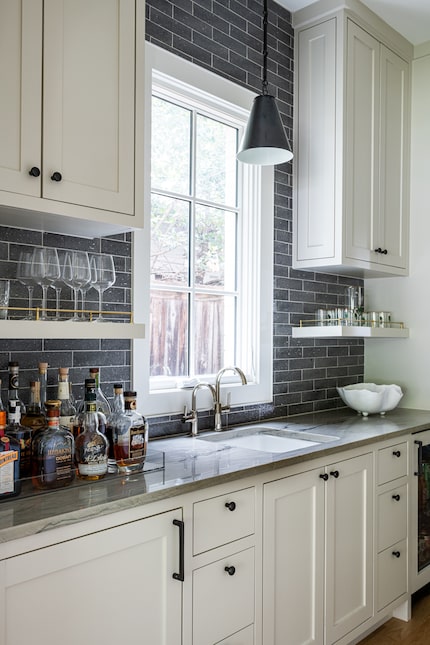 Butler's pantry with white cabinets and a window, with a light over the sink