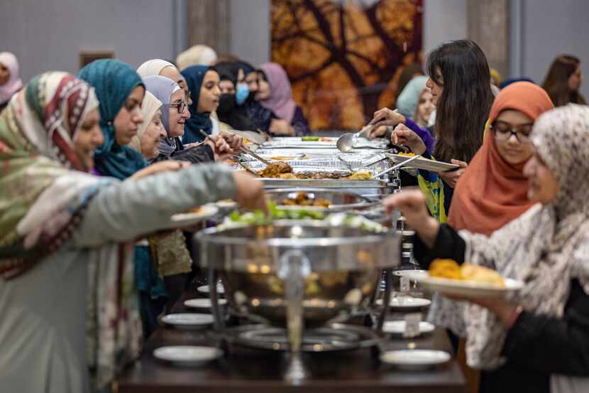 Women line up at a buffet during a DFW Refugee Outreach Services fundraiser on Sunday in...