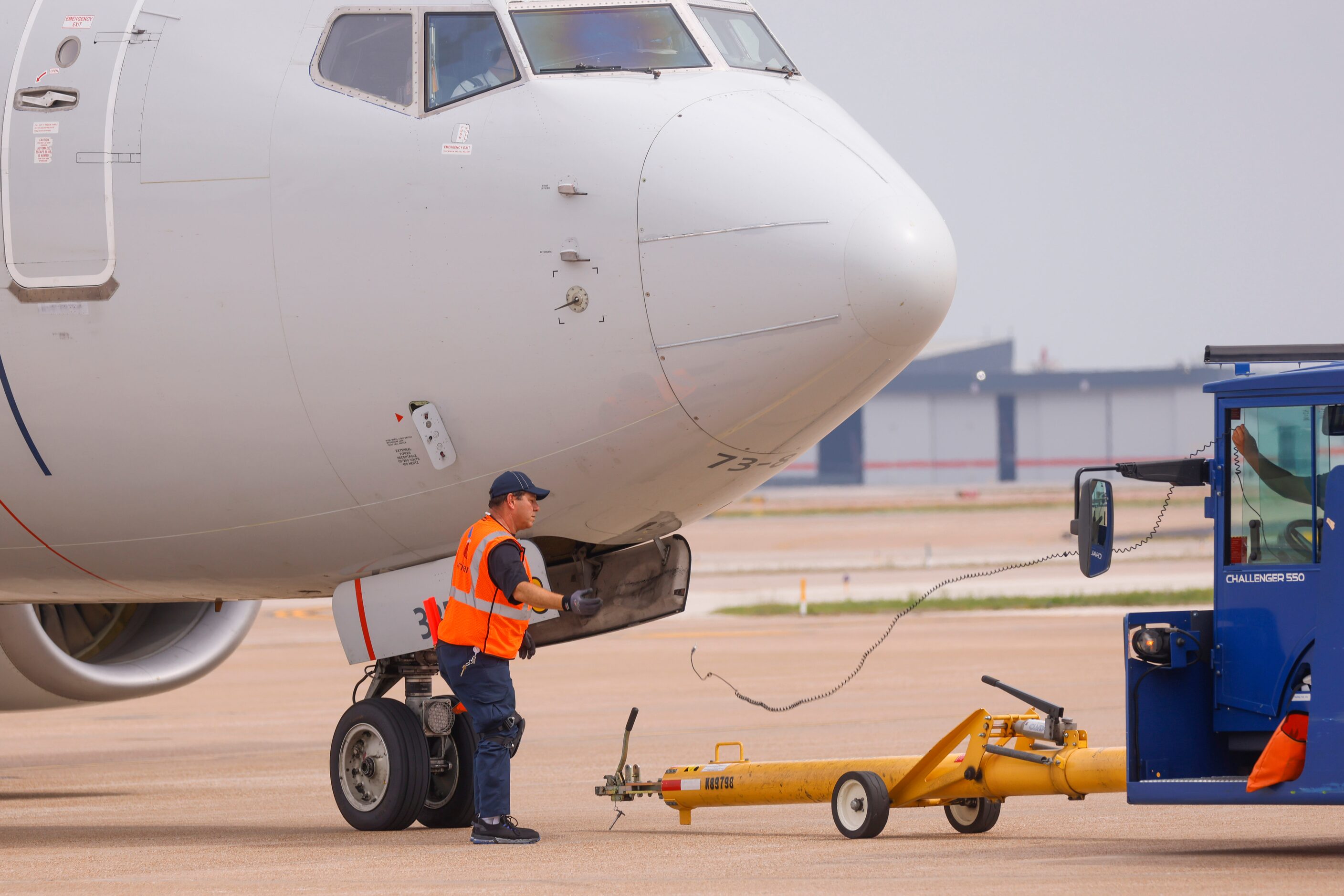 Members of the ground crew detach a pushback tractor from American Airlines flight to...