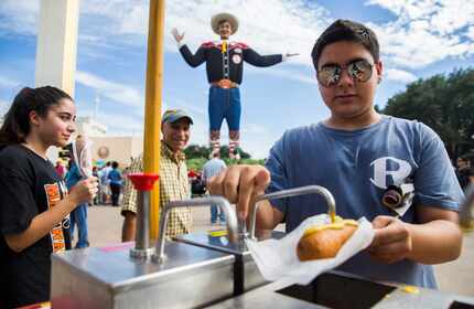 Matthew Kianpour, 15, right of Rockwall, Texas, tops his Fletcher's Corny Dog with mustard...