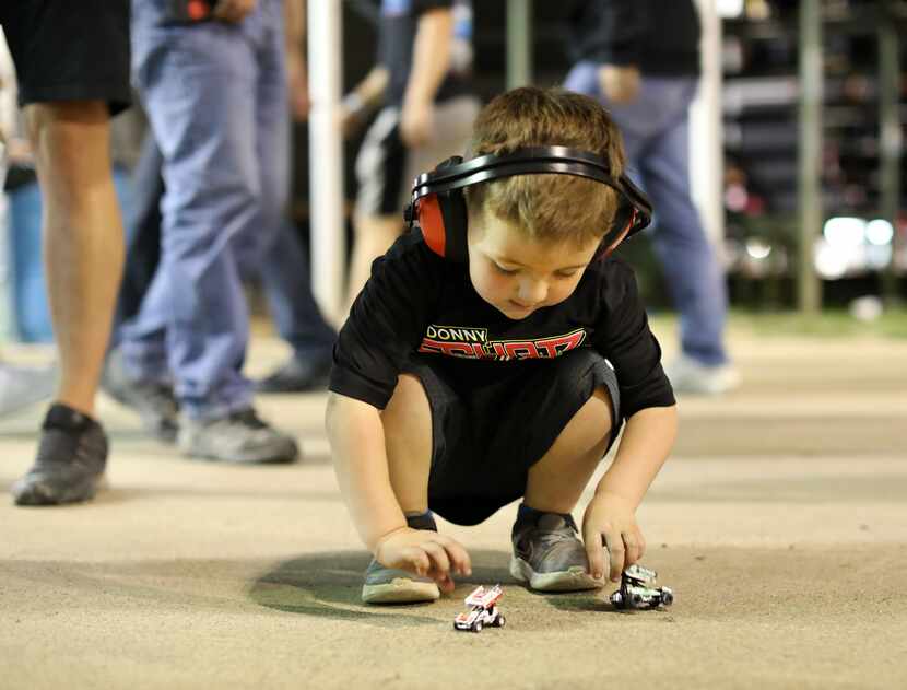 Four-year-old Easton Obregon plays with his toy sprint cars at Devil's Bowl Speedway in...