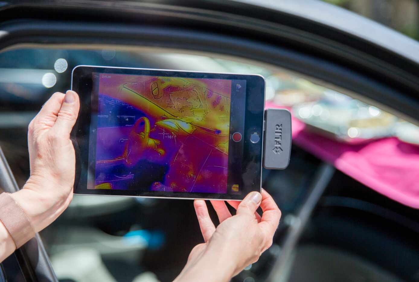 Mary Urquhart holds a thermal camera showing how hot a car left in the Texas sun gets.