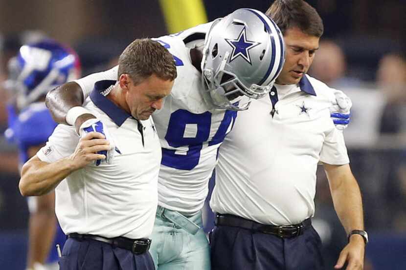 Dallas Cowboys defensive end Randy Gregory (94) is helped off the field by trainers after...