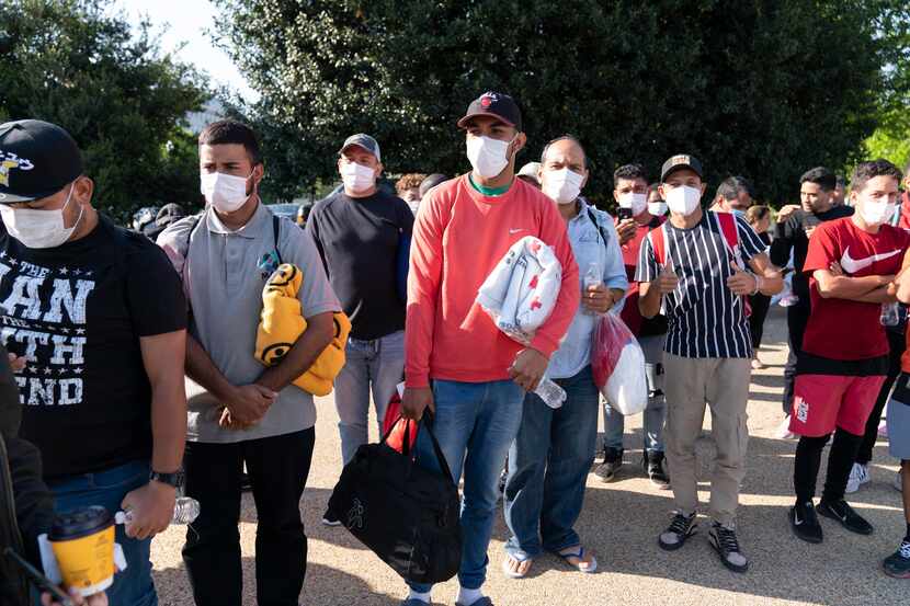 Migrantes con frazadas de la Cruz Roja después de llegar en autobuses procedentes de Texas a...