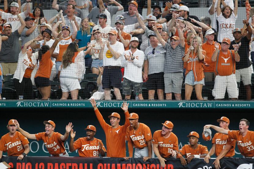 Texas Longhorns players celebrate a multiple run scoring hit as fans over their dugout voice...