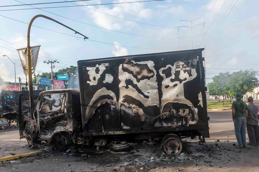 This Oct. 18, 2019, photo shows a burnt out truck used by gunmen smoldering on an...
