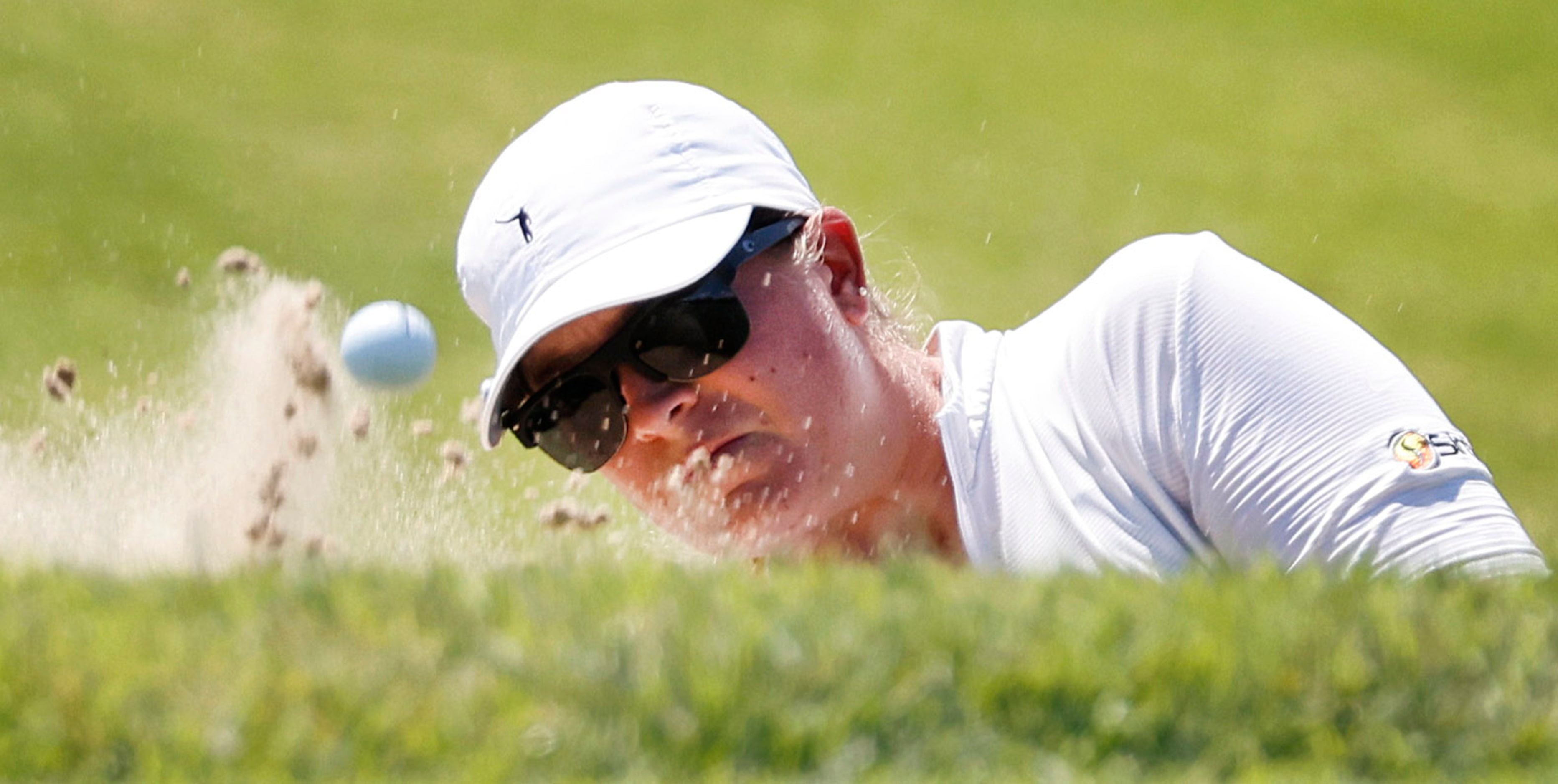 Professional golfer Lauren Coughlin hits out of the green side bunker on No. 17 during the...