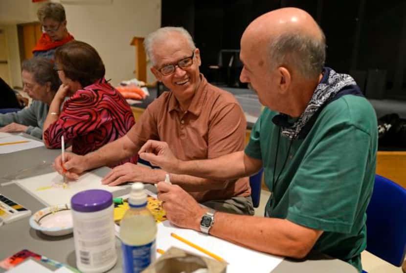 
Volunteer David Oge (right) sits with George Esterly while he paints during the Memories in...