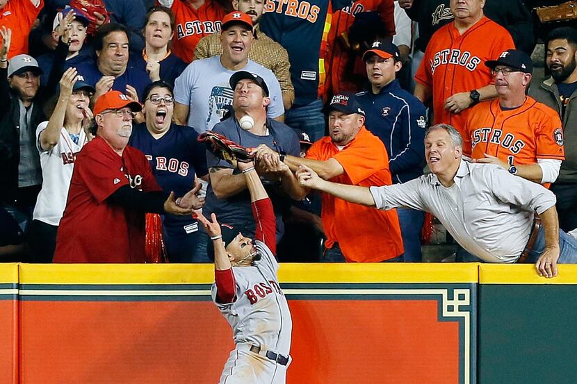 A fan interferes with Mookie Betts #50 of the Boston Red Sox as he attempts to catch a ball...