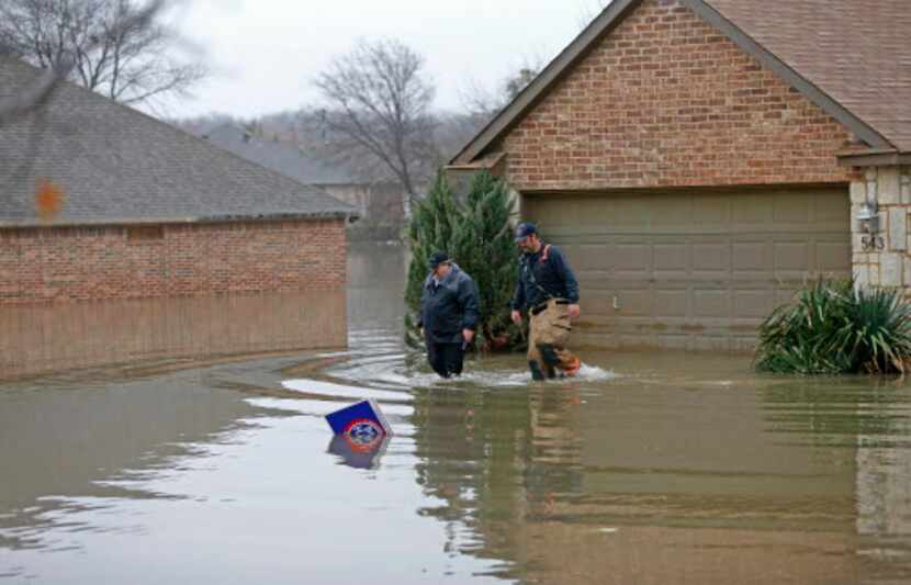 Rodger Williams (izq.) deja su inundada casa con ayuda de los bomberos de Rockwall. DMN