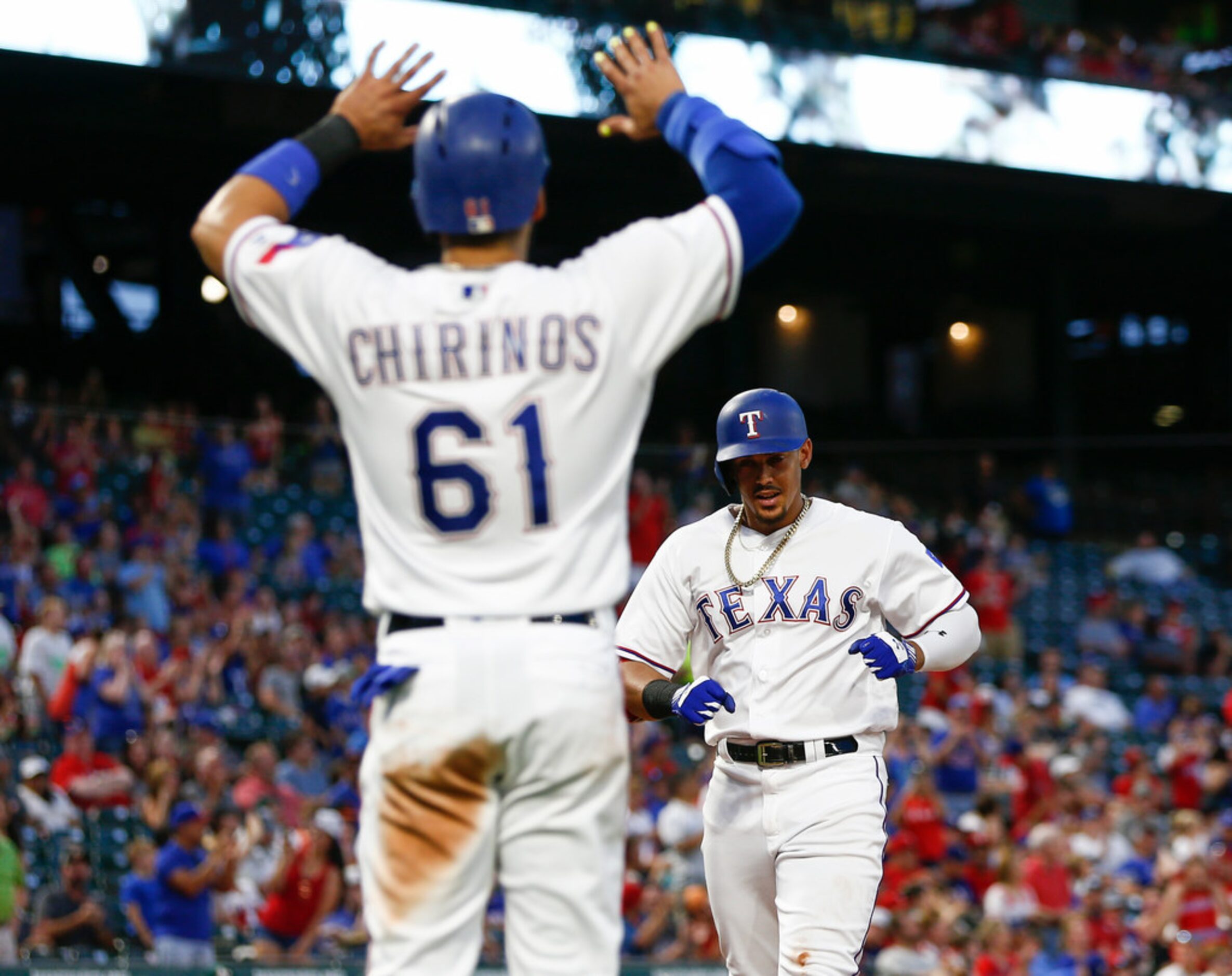 Texas Rangers' Ronald Guzman, rear, arrives home on his two-run home run as Robinson...