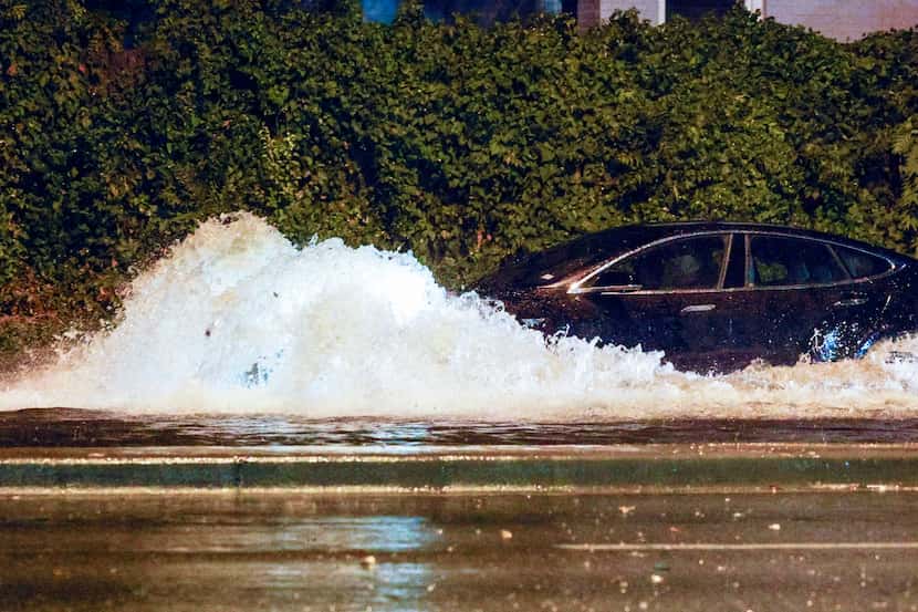 Cars drive through a flooded section of Garland Road near North Buckner Boulevard during a...