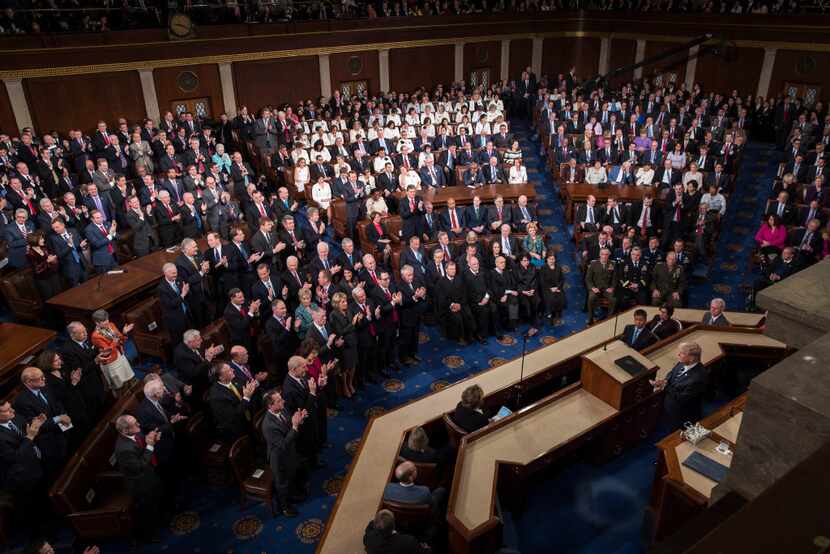 Republicans applaud at left as most Democrats remain seated as President Donald Trump...
