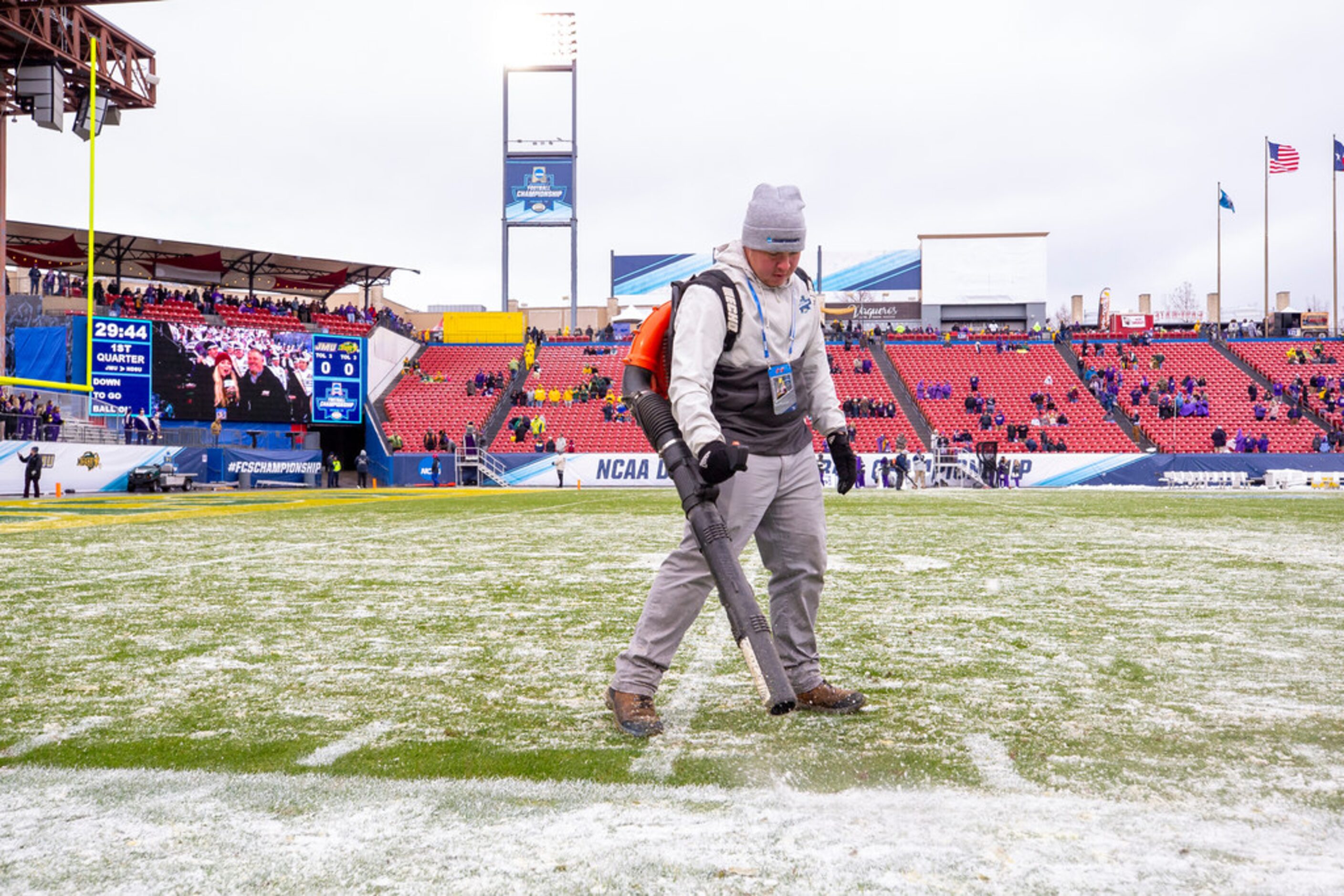 A worker blows snow off the field before the FCS championship NCAA college football game...