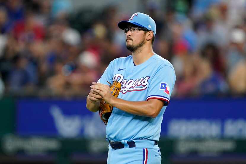 Texas Rangers starting pitcher Dane Dunning walks behind the mound as he works in the second...