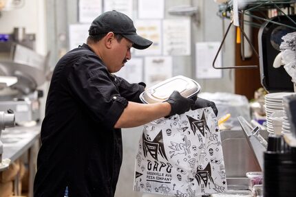 Miguel Acosta, a prep cook at Greenville Avenue Pizza Company, loads an Uber Eats pick-up...