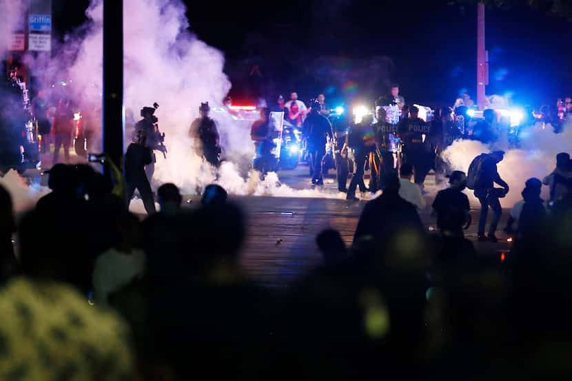 Dallas police attempt to disperse the crowd of protesters along Young Street and Griffin in...