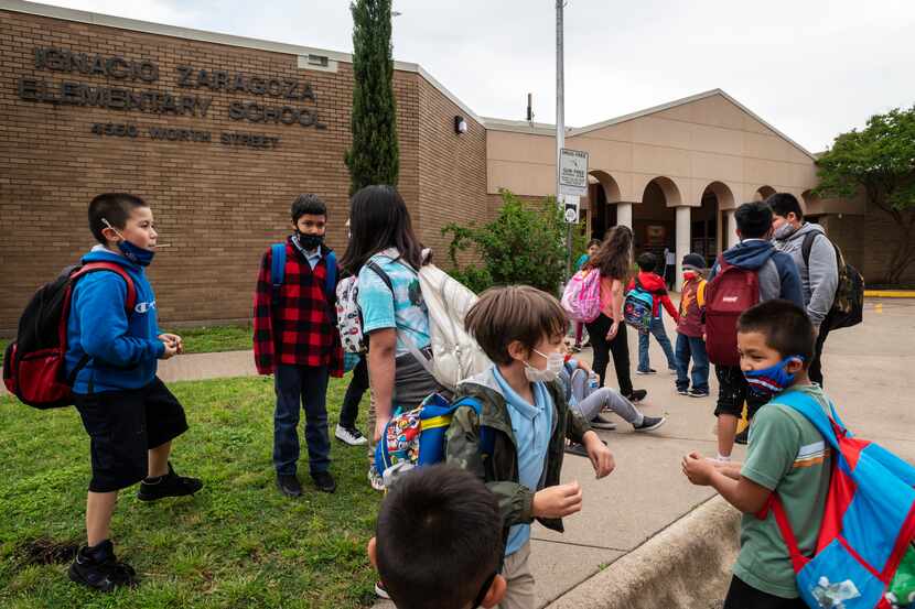A group of students wearing face masks play outside of Ignacio Zaragoza Elementary School as...