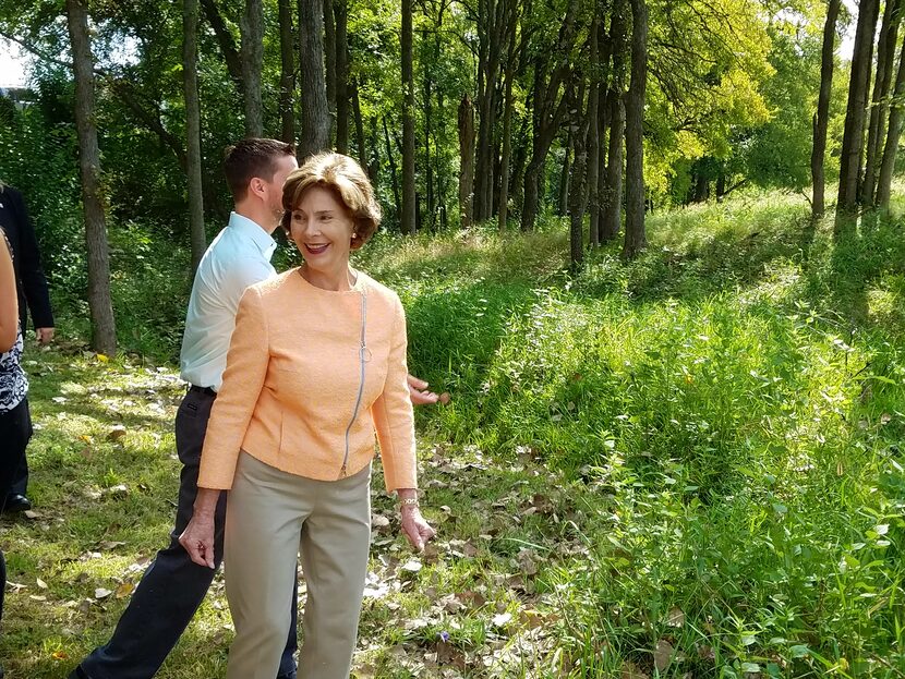 Former first lady Laura Bush helps spread milkweed seed balls at an Austin office park where...