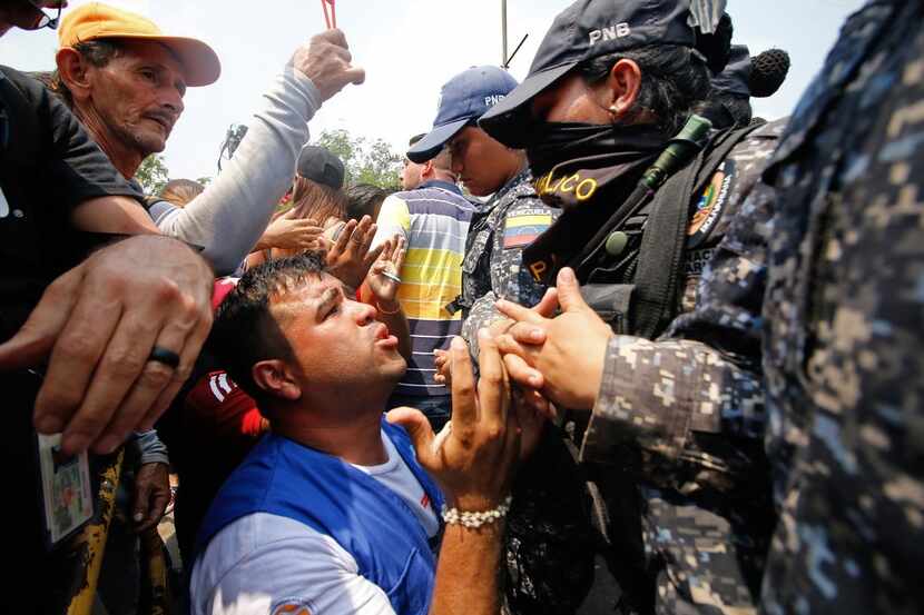 A supporter of Venezuela's opposition leader Juan Guaido kneels in front of members of...
