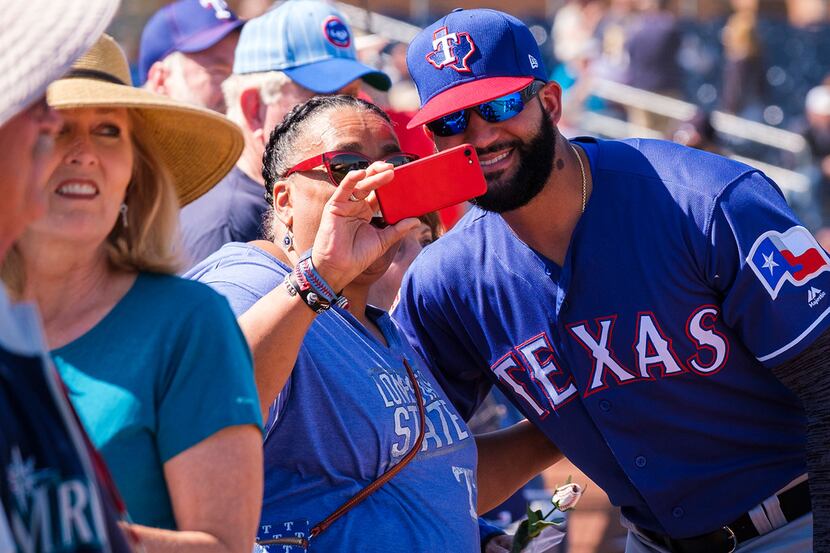 Texas Rangers outfielder Nomar Mazara poses for a photo with a fan before a spring training...