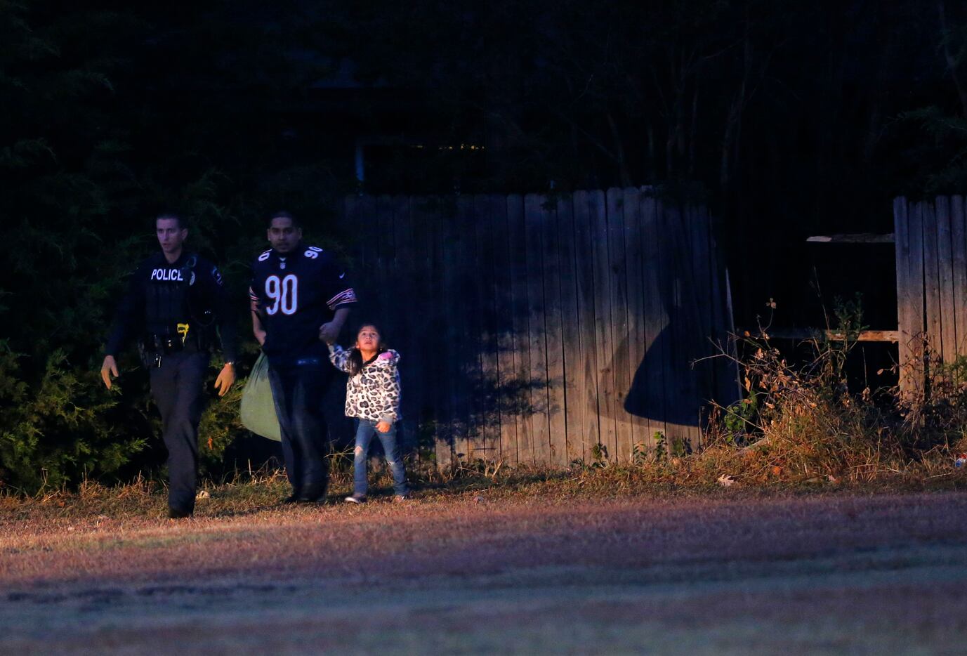 A parent and child are escorted through a fence in an Arlington neighborhood where a police...