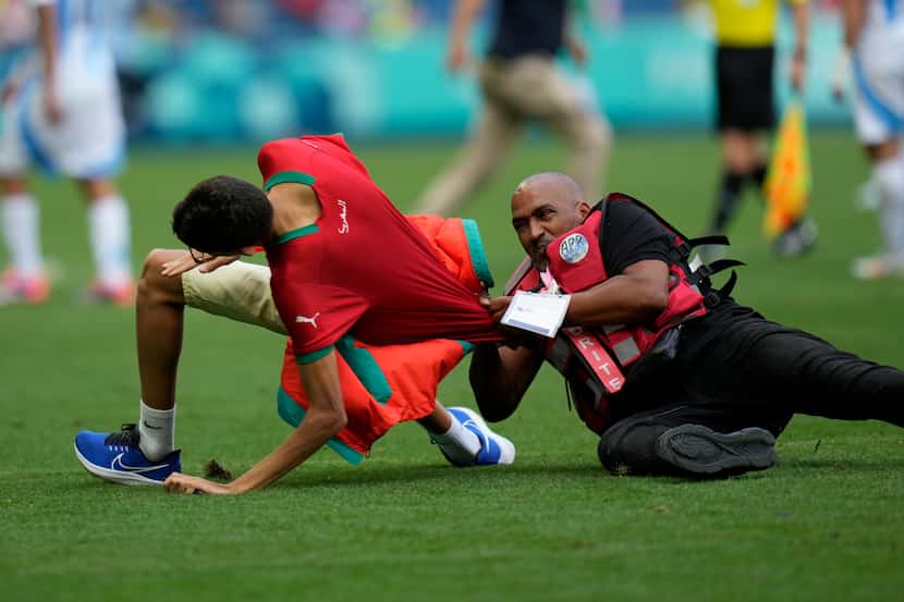 A steward catches a pitch invader during the men's Group B soccer match between Argentina...