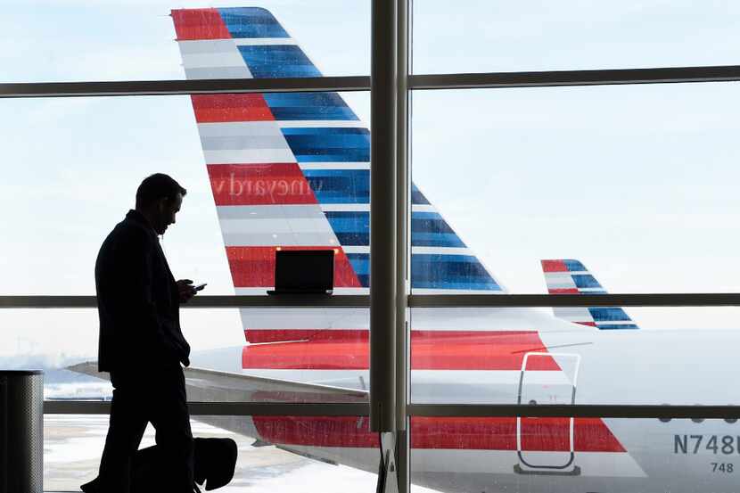 FILE - In this Jan. 25, 2016, file photo, a passenger talks on the phone as American...
