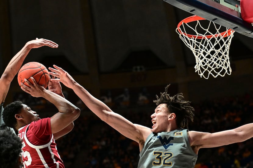 Oklahoma guard Grant Sherfield (25) shoots while being guarded by West Virginia forward Tre...