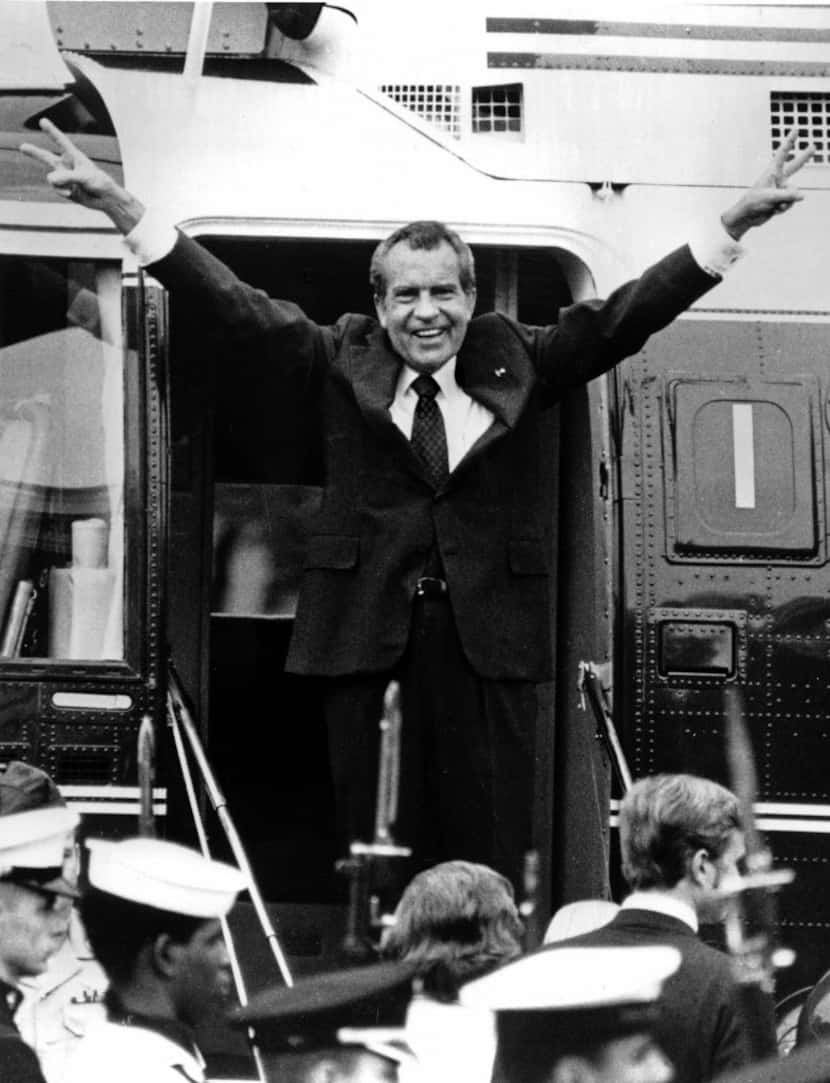Richard Nixon waves goodbye with a salute to his staff members outside the White House as he...