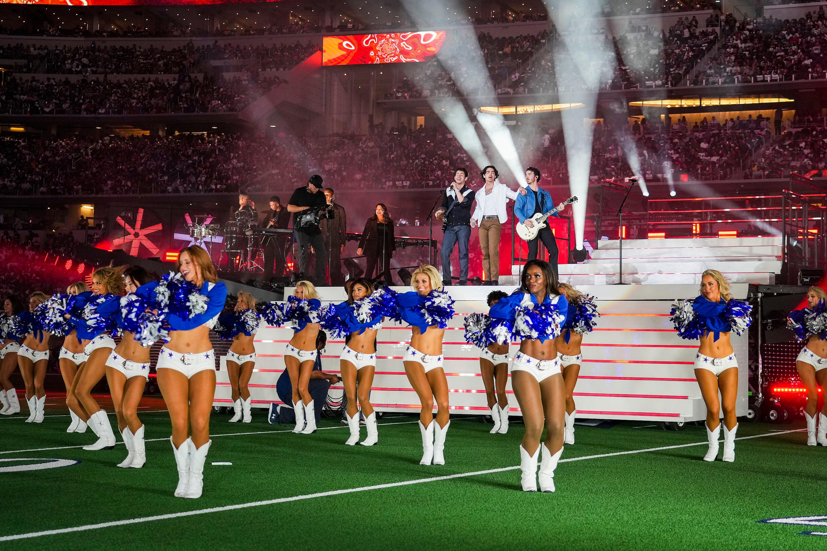 The Jonas Brothers perform with the Dallas Cowboys cheerleaders during halftime of an NFL...