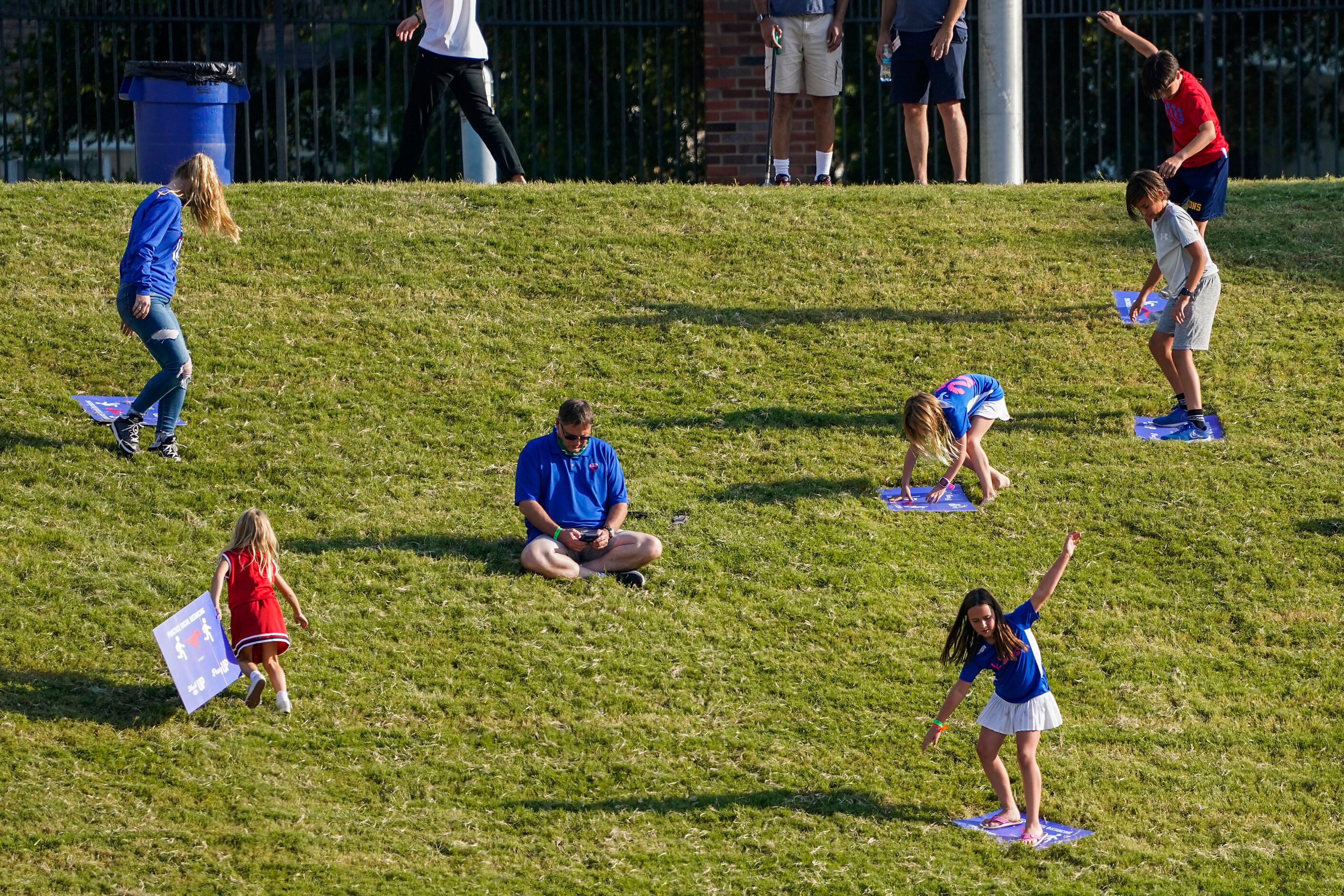 Children use social distancing signs to slide down the hill in the south end zone during the...