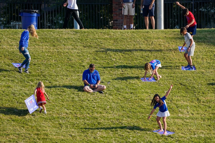 Children use social distancing signs to slide down the hill in the south end zone during the...