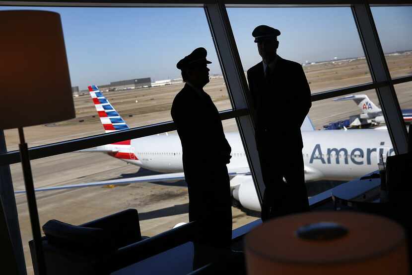 U.S. Airways pilots visit while in the background a newly painted American Airlines 777 is...