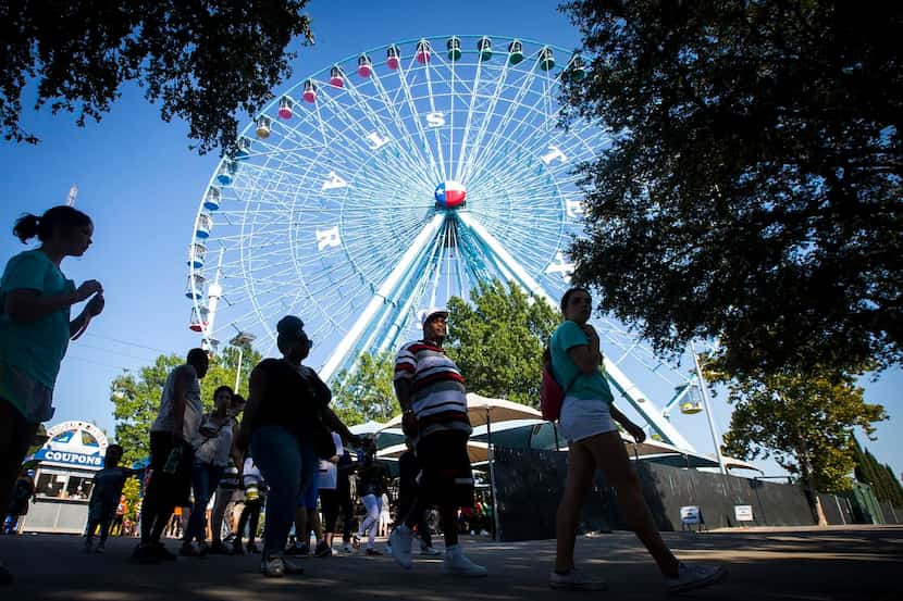 
Fairgoers pass the Texas Star ferris wheel during the State Fair of Texas at Fair Park in...