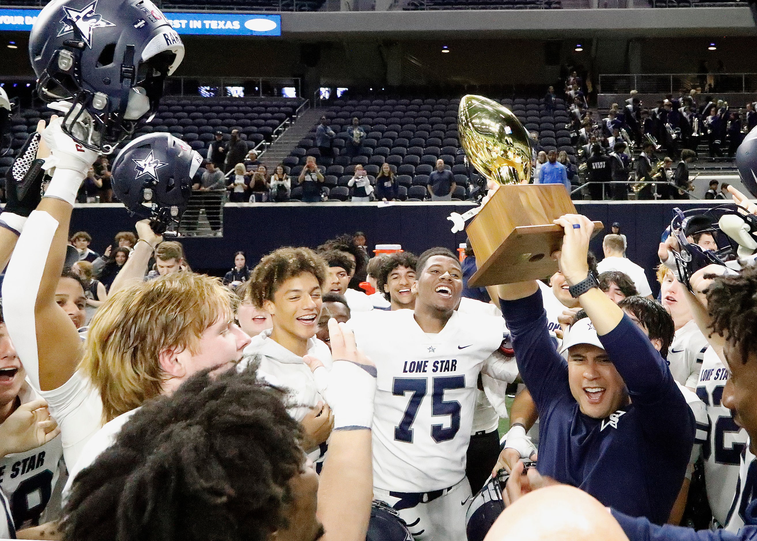 Lone Star High School head coach Jeff Rayburn hoists up their district trophy after Reedy...