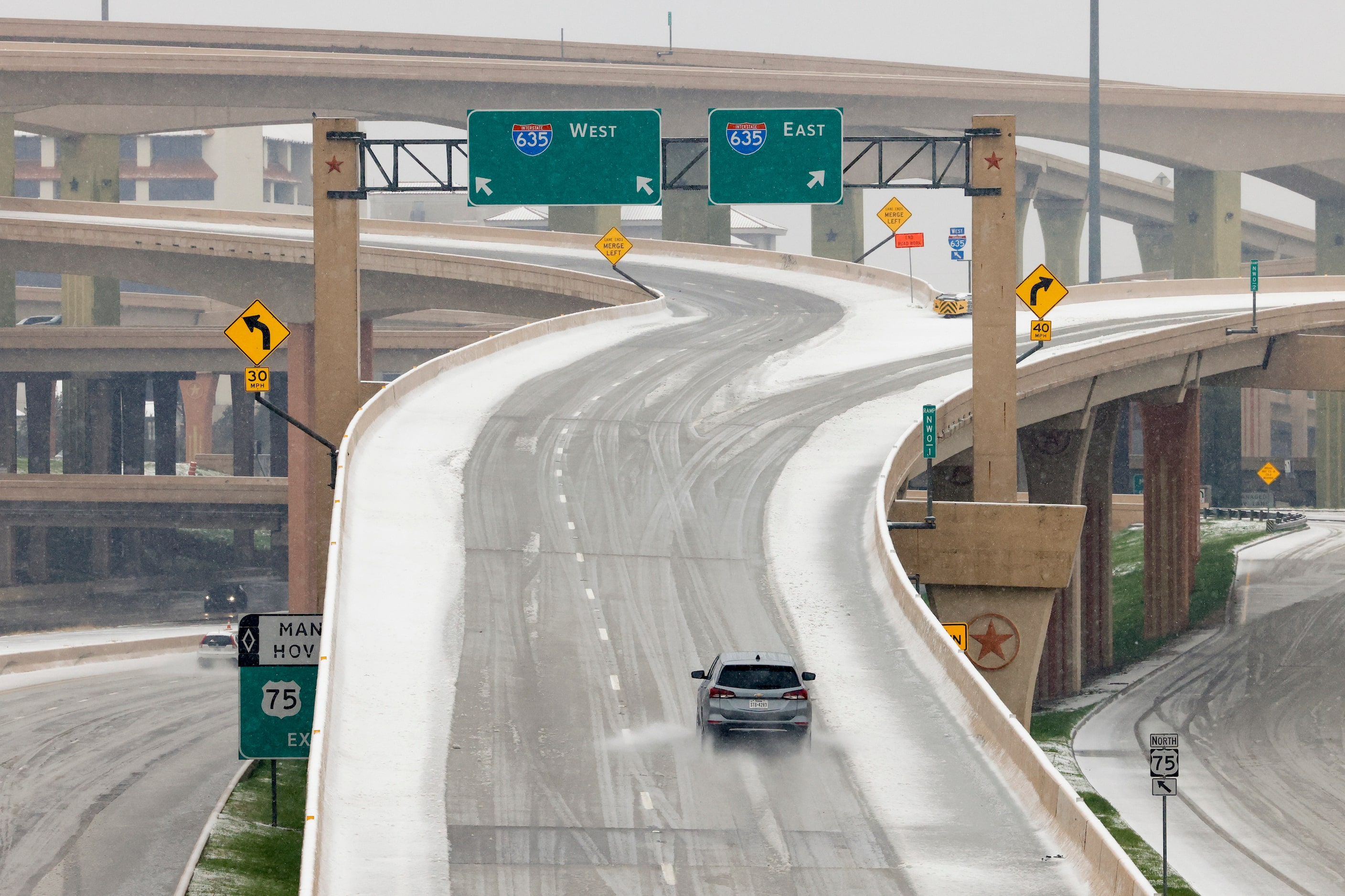 A vehicle drives on an icy overpass at the High-Five interchange at Interstate 635 and U.S....