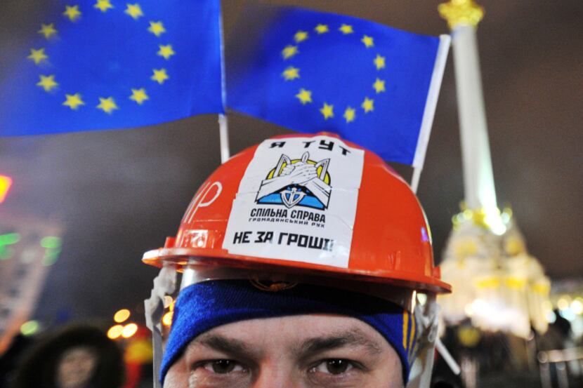 A man wearing a construction work helmet decorated with European Union flags takes part in...