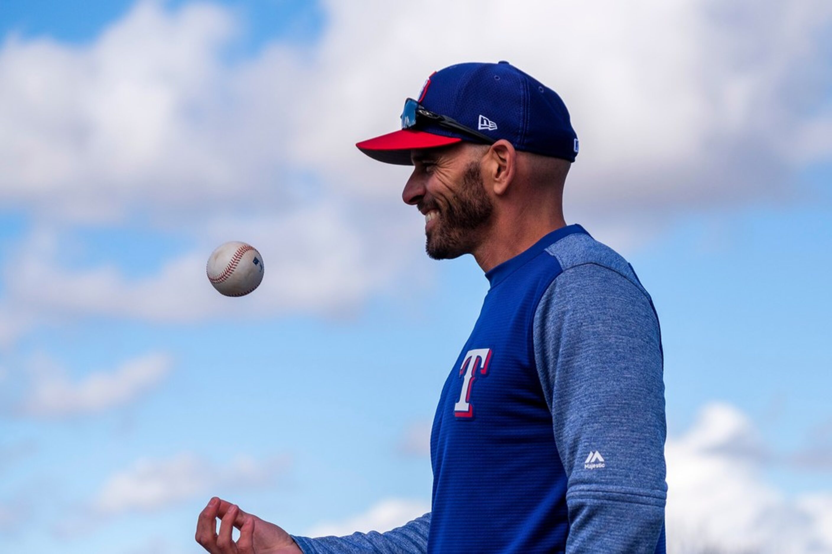 Texas Rangers manager Chris Woodward tosses a ball as he watches his team during the first...