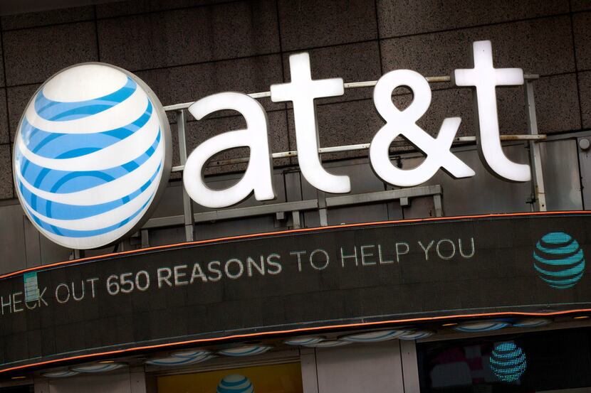 FILE - In this Oct. 24, 2016, file photo, the AT&T logo is positioned above one of its...